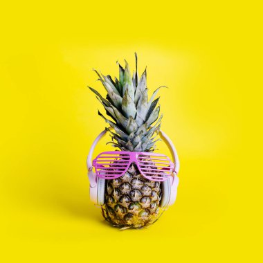 Güneş gözlüğü ve kulaklık ile moda trendy ananas meyve parlak pastel sarı arka plan üzerinde müzik dinleyin. Komik surat ile serin hipster ananas. Yaz tatil tatil ve tropikal plaj partisi konsepti.