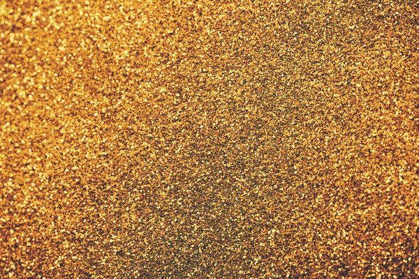 Golden glitter textured background for christmas and new year celebration party. Gold dust sparkling texture top view. Luxury and glamour bronze and brass pattern backdrop.