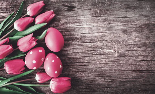 Huevos rojos de Pascua y flor de tulipán rosa en mesa de madera vintage fr — Foto de Stock