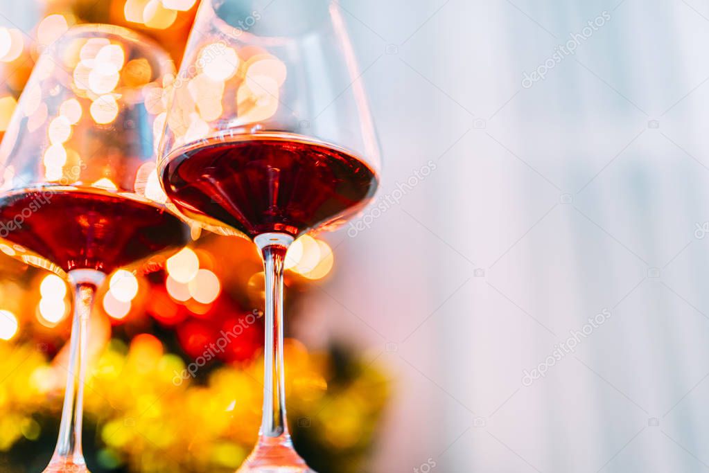 Two glass of red wine in front of christmas tree lights bokeh. N