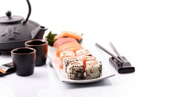 Beyaz arka planda izole edilmiş bambu yemek çubuğu çerçeveli suşi kabı yakın plan. Sashimi, maki, surimi, çaydanlık, sake ve soya soslu lüks Japon restoranı yemeği. Klas Japon yemekleri ton balığı, deniz ürünleri, somon balığı, av