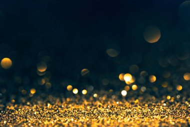 Lüks, soyut, ışıltılı, gösterişli bir arka plan. Yeni yıl ve noel partisi tasarımı. Koyu arkaplanda parıldayan altın yıldız tozu ışığı.