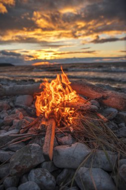 Gün batımında denize yakın bir ateş yakar.