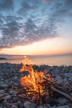 Gün batımında denize yakın bir ateş yakar.