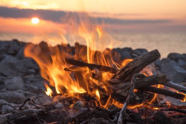 Gün batımında denize yakın bir ateş yakar.