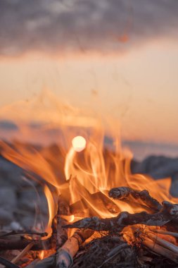 Gün batımında denize yakın bir ateş yakar.