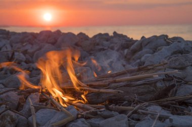 Gün batımında denize yakın bir ateş yakar.