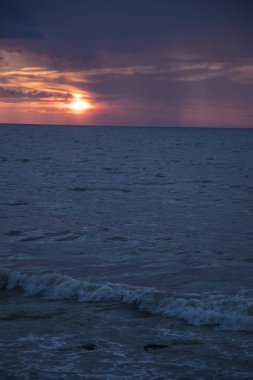 Denizde gün batımı. Yağmur yağıyor.