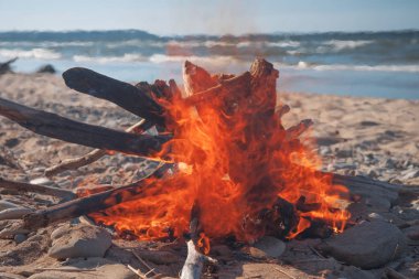 Gün batımında denize yakın bir ateş yakar.