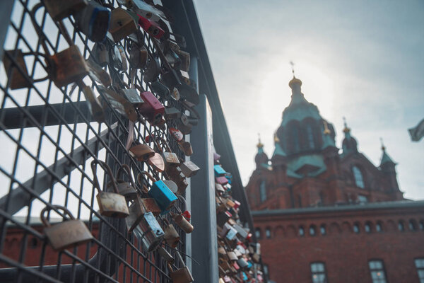 Hanging locks on the bridge on the background of the Uspensky Cathedral of Helsinki