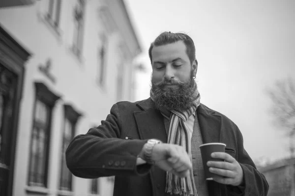 man with a beard looks at his watch. black and white photo.