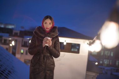 Güzel Asyalı kız, gece vakti kahve içiyor ve şehirde yürüyor.