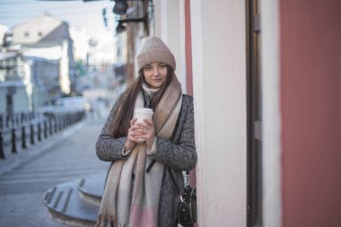 Paltolu ve kahveli bir kız şehirde yürüyor.