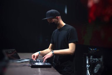 Maskeli DJ salgın bir partide müzik çalıyor..