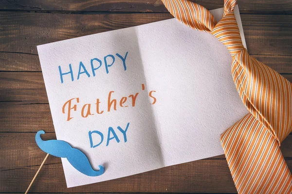 Happy father\'s day! Postcard and tie on background of wooden table.