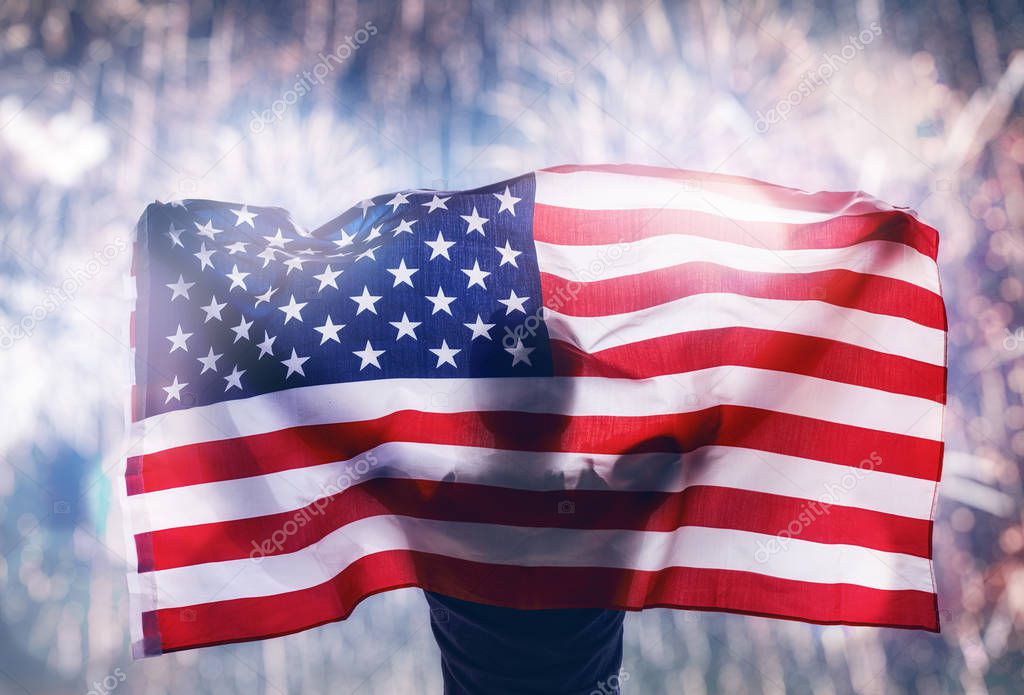 Patriotic holiday. Happy young man with American flag looking at fireworks. USA celebrate 4th of July.