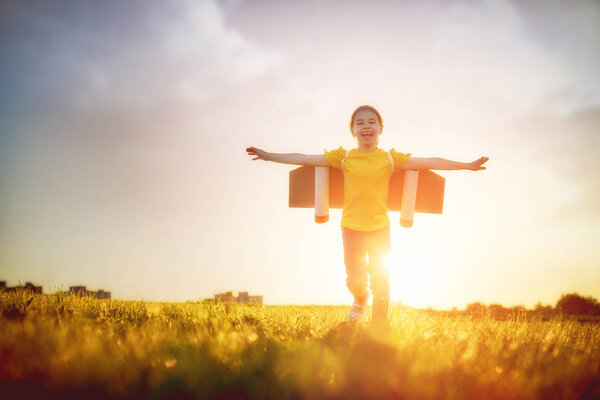 Little girl playing astronaut. Child fleeing on the background of sunset sky. Kid dreaming of becoming a spaceman.