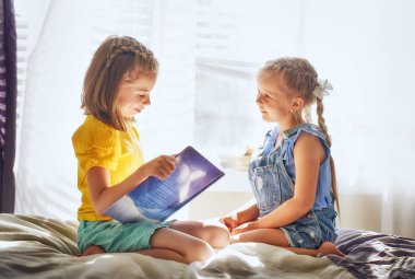 Şirin çocuk kızlar evde oda üzerine bir kitap okuma.