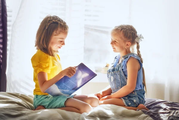 Şirin çocuk kızlar evde oda üzerine bir kitap okuma.