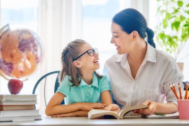 Mutlu bir aile. Anne ve kızı bir kitap okuyor. Okula dönüş.