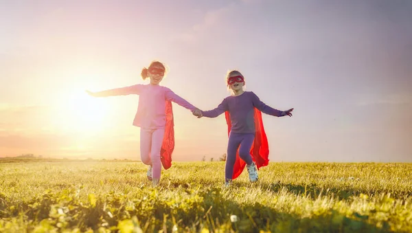 Süper kahraman oynayan iki küçük çocuklar. Çocuklar günbatımı gökyüzü arka plan üzerinde. Kız güç kavramı
