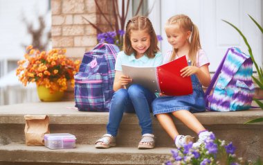 Öğrenciler İlköğretim Okulu ile el yaptırın. Açık havada bina yakınındaki sırt çantaları kızlarla. Ders başlangıcı. Sonbaharın ilk günü.