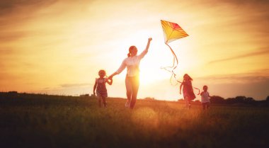 Mutlu bir aile açık oynuyor. Anne ve çocuk niteliğine yaz aylarında çayır bir uçurtma ile çalışan.
