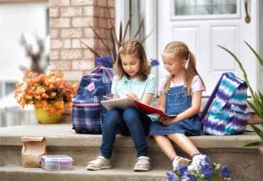 Öğrenciler İlköğretim Okulu ile el yaptırın. Açık havada bina yakınındaki sırt çantaları kızlarla. Ders başlangıcı. Sonbaharın ilk günü.