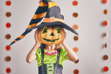 Cadılar Bayramınız Kutlu Olsun! Sevimli küçük gülen kız cadı kostüm balkabağı ile.