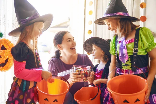 幸せな家族は ハロウィーンを祝う 若いお母さんは お菓子と子供を扱います 面白い子供たちのカーニバル衣装 — ストック写真