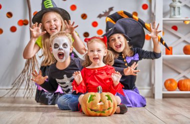 Mutlu kardeşi ve üç kız Halloween. Komik çocuk kapalı karnaval kostümleri. Kabaklar ve şeker ile neşeli çocuk oyun.