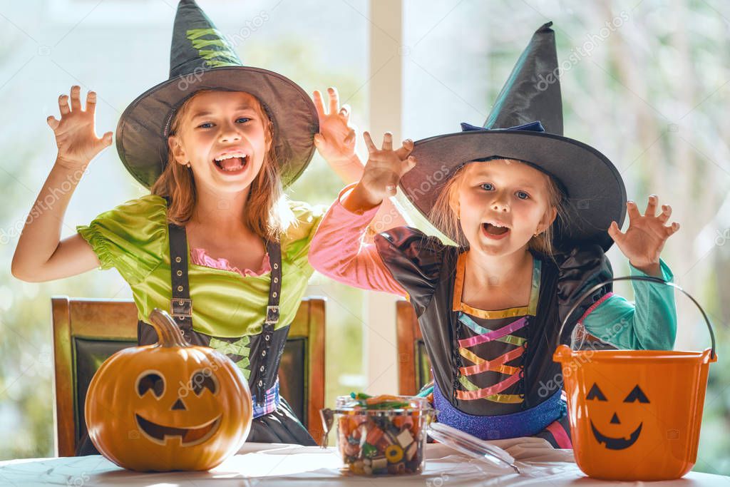 Cute little children girls with carving pumpkin. Happy family preparing for Halloween. Funny kids at home.