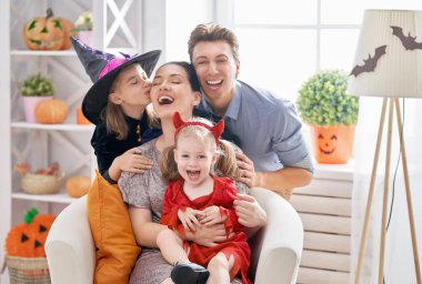 Anne, baba ve çocukları evde eğleniyor. Cadılar Bayramı kutluyor mutlu bir aile. Karnaval kostümleri giyen çocuk.