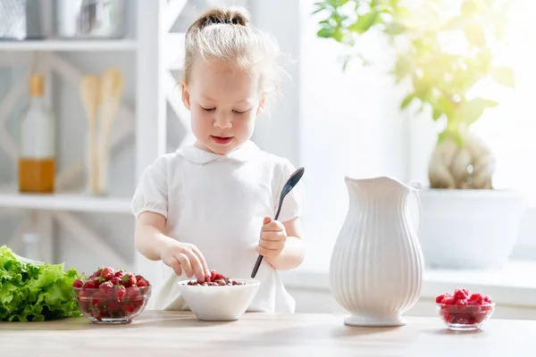 朝食を食べて幸せな子 子供の食べる穀物とキッチンのベリー — ストック写真