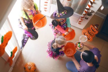 Cadılar Bayramı kutluyor mutlu bir aile! Genç anne çocuk şeker ile davranır. Komik çocuk karnaval kostümleri.