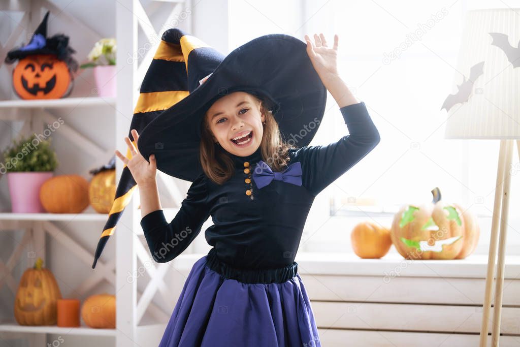 Happy Halloween! Cute little laughing girl in witch costume.