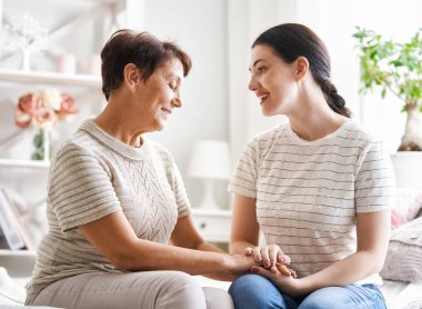 Güzel anne ve kız evdeki kanepede otururken sarılıyor, konuşuyor ve gülümsüyor..