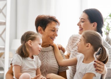 Güzel kız, annesi ve büyükannesi güneşli sabah keyfini çıkarın. Evde iyi zaman. Yatak odasında oynarken aile.