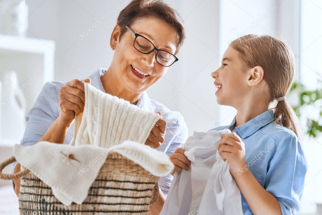 Beautiful women and child girl little helper are having fun and smiling while doing laundry at home.