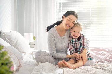Güzel bir kız bebek ve annesi güneşli bir sabahın tadını çıkarıyorlar. Evde iyi vakit geçir.. 