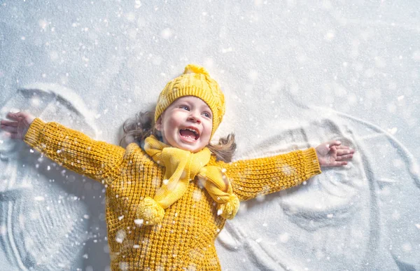 自然の中で冬の散歩で遊んで幸せな子供の女の子 雪の天使を作る子供 — ストック写真