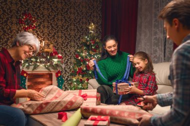 Mutlu Noeller ve mutlu yeni yıl! Büyükanne, Anne, baba ve kızı yakın ağaç evde. Aile Tatil Hazırlanma.