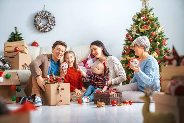 Merry Christmas and Happy Holidays!  Granny, mother, father and children decorate the tree in room. Loving family indoors.