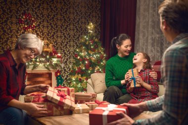 Mutlu Noeller ve mutlu tatiller! Büyükanne, Anne, baba ve çocuk hediye alışverişi. Anne ve kızı kapalı tree yakınındaki eğleniyor. Sevgi dolu aile ile odada sunar.