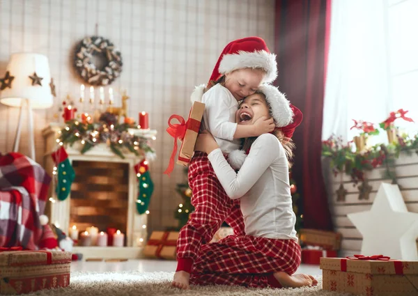 メリー クリスマスとハッピー ホリデー 陽気なかわいい子供の女の子がプレゼントを開きます 朝の木の近く楽しんでパジャマを着て子供たち 部屋で愛する家族を提示します — ストック写真