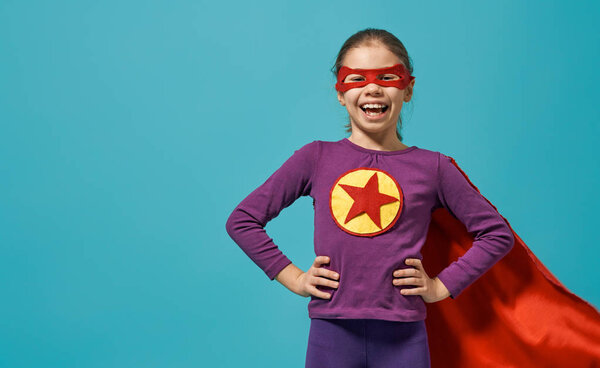 Малыш играет в супергероя. Парень на фоне ярко-голубой стены. Концепция власти девочек
.