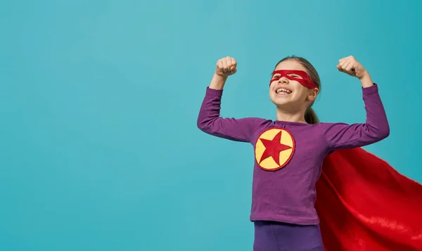 小さな子供は スーパー ヒーローを果たしています 明るい水色の壁の背景を子供します 女の子パワー コンセプト — ストック写真