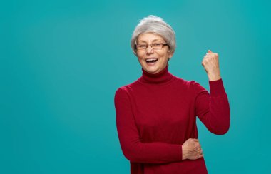 Kadın kırmızı kazaklı turkuaz arka plan üzerinde poz kıdemli neşeli güzel.