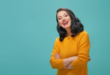 Sarı kazaklı turkuaz arka plan üzerinde poz neşeli güzel ve genç birbayan.