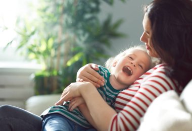 Anneler Günün kutlu olsun! Anne ve kızı oynuyorlar, gülümsüyorlar ve sarılıyorlar. Aile tatili ve birliktelik.